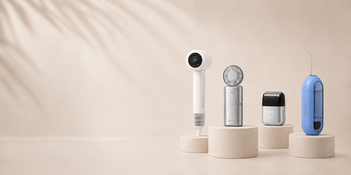 Four modern grooming devices displayed on round pedestals against a warm beige background with soft leaf shadows. The devices include a white handheld device, a silver-and-white circular device, a small black-and-silver rectangular device, and a blue handheld device.