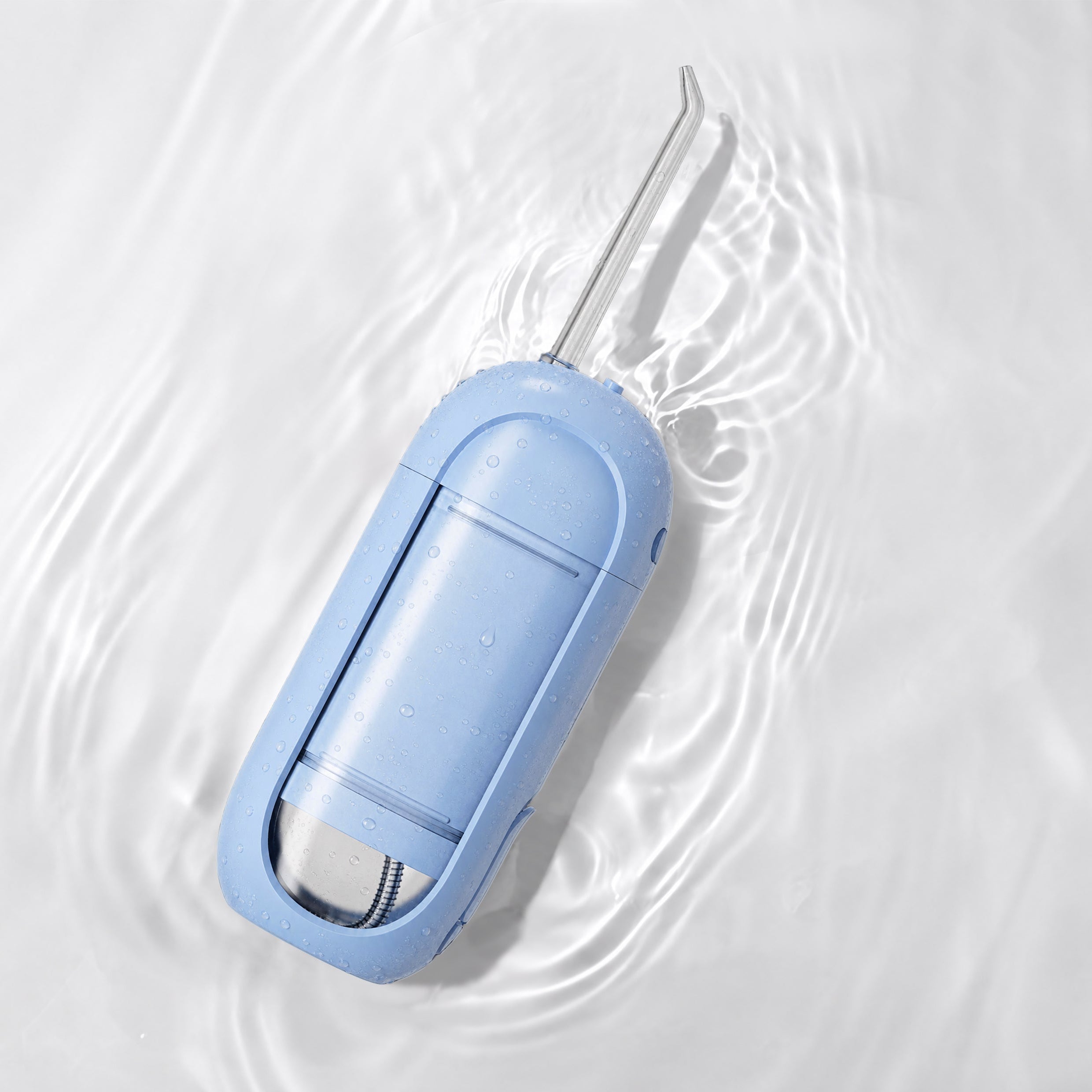 A light blue flossing device with a silver metal flossing arm, resting on ripples of water on a white background.