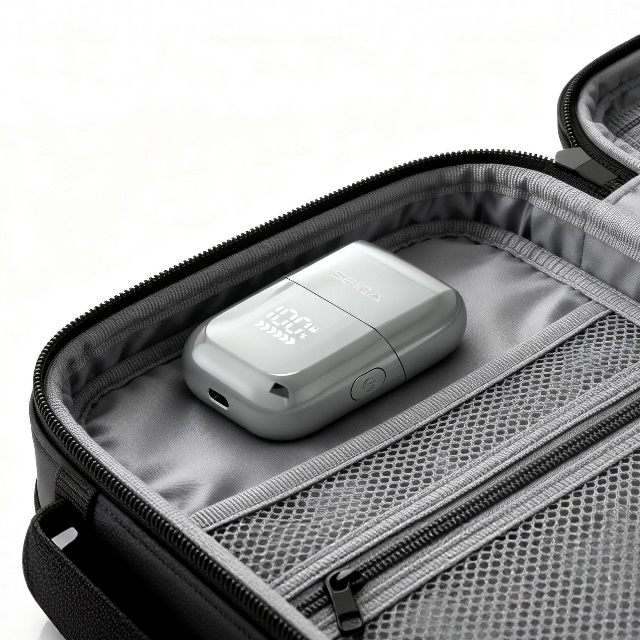 A silver rectangular electronic device with a USB-C port resting inside a gray zippered travel organizer bag with mesh pockets.